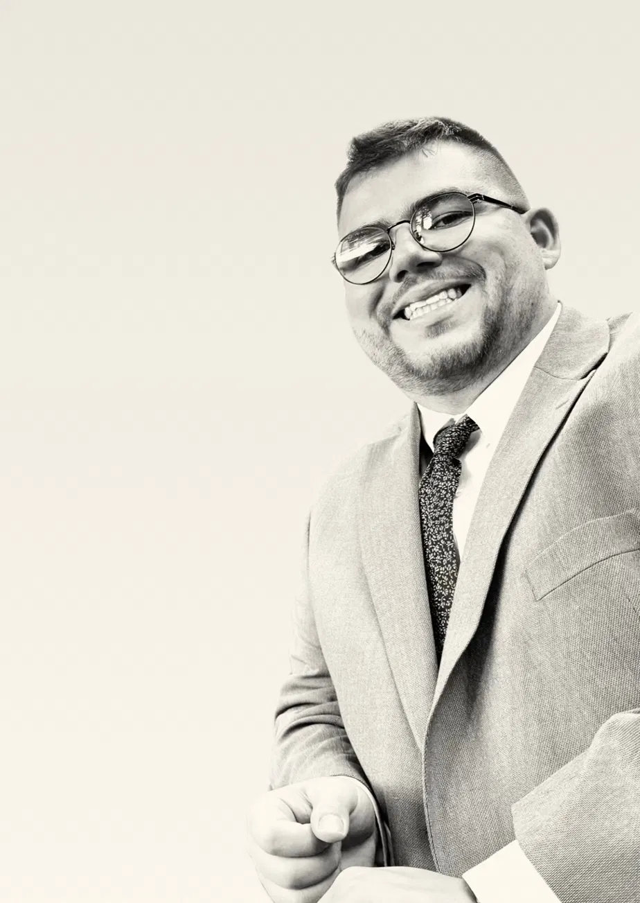 Portrait of Nicholas Bone, smiling, wearing glasses and a suit.